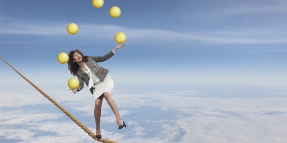 Mixed race businesswoman juggling on tightrope